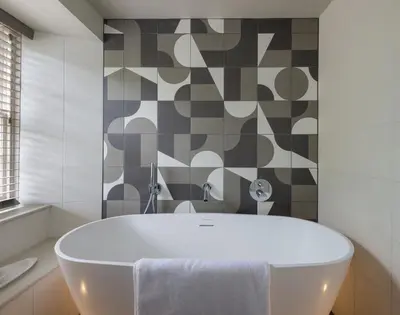 a white tub in a bathroom with a tile wall at Crow's Nest in Port Isaac