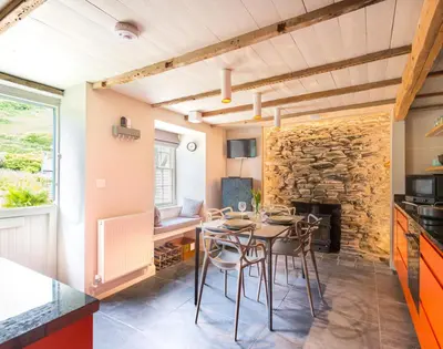 a dining room with a table and a stone fireplace at Crow's Nest in Port Isaac