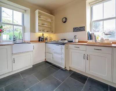 a large kitchen with white cabinets and a sink at Worthy House in Polzeath