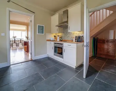 a kitchen with white cabinets and a tile floor at Worthy House in Polzeath