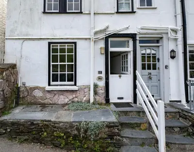a white house with a white door and stairs at April Cottage in Port Isaac