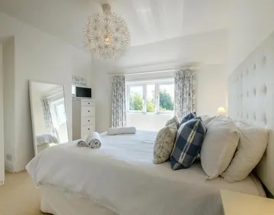 a bedroom with a large white bed with a chandelier at The Moorings in Padstow