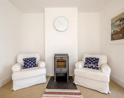a living room with two chairs and a stove at The Moorings in Padstow