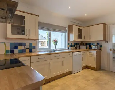 a kitchen with white cabinets and a vase of flowers at The Moorings in Padstow