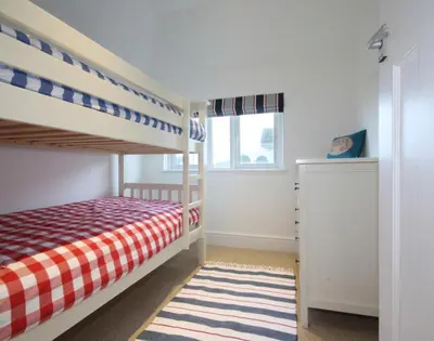 a bedroom with a bunk bed with a checkered blanket at The Moorings in Padstow