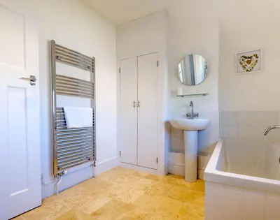 a white bathroom with a sink and a tub at The Moorings in Padstow