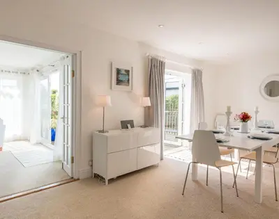 a white dining room with a table and chairs at The Moorings in Padstow