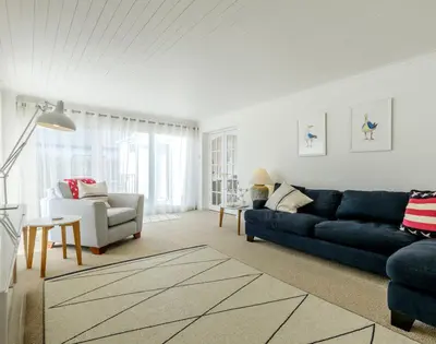 a living room with a blue couch and a chair at The Moorings in Padstow