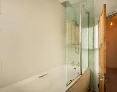 a bathroom with a shower and a tub and a sink at Kipper Cottage in Port Isaac