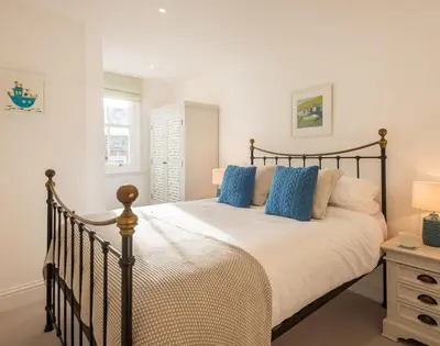 a bedroom with a large bed with blue pillows at Kipper Cottage in Port Isaac
