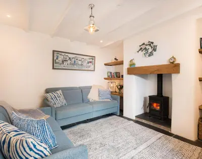 a living room with a blue couch and a fireplace at Kipper Cottage in Port Isaac
