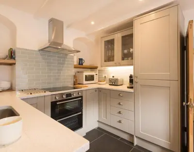 a kitchen with white cabinets and a stove top oven at Kipper Cottage in Port Isaac