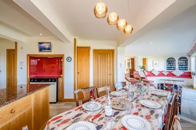 a dining room with a table and a kitchen at Trevan House Lundy in Polzeath