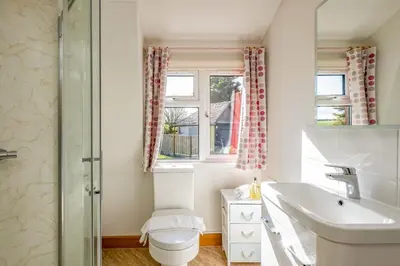a bathroom with a sink and a toilet and a window at Trevan House Lundy in Polzeath