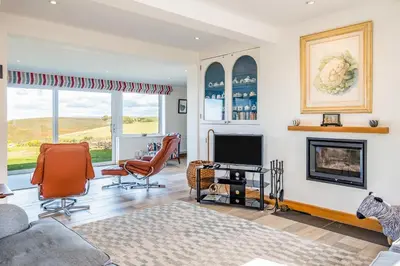 a living room with a fireplace and a tv at Trevan House Lundy in Polzeath