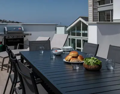 a table with a plate of bread and vegetables on a balcony at Point Break in Polzeath