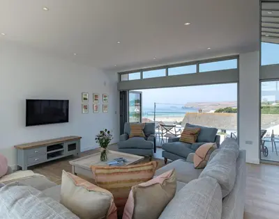 a living room with a couch and a tv and a table at Point Break in Polzeath