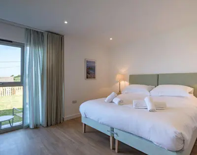 a bedroom with a large bed and a large window at Point Break in Polzeath