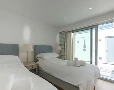 two beds in a room with a window at Point Break in Polzeath
