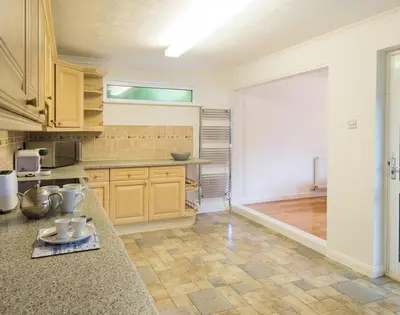 a large kitchen with wooden cabinets and a counter top at Greenaway, 4 Rockhaven Gardens in Saint Minver