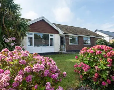 a house with pink flowers in the yard at Greenaway, 4 Rockhaven Gardens in Saint Minver