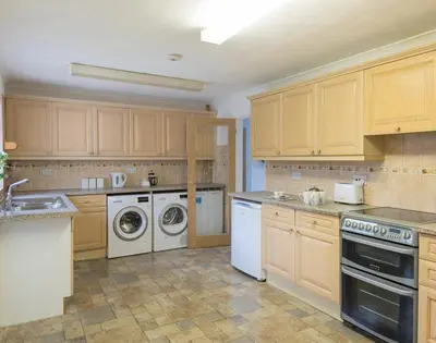 a kitchen with white appliances and wooden cabinets at Greenaway, 4 Rockhaven Gardens in Saint Minver