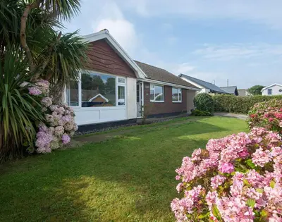 a house with pink flowers in the yard at Greenaway, 4 Rockhaven Gardens in Saint Minver