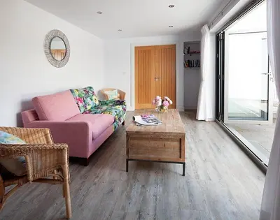 a living room with a pink couch and a coffee table at The Crows Nest in Port Isaac