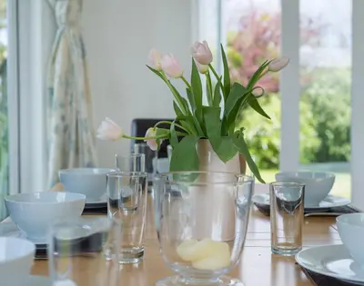 a table with a vase with pink flowers in it at Penny Liggan in Padstow