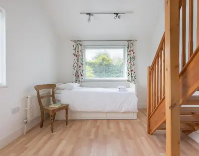 a bedroom with a bed and a window and a chair at Penny Liggan in Padstow