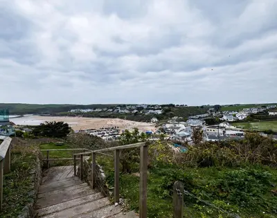 a wooden staircase leading to a beach with a town at Pinewood 14 in Polzeath