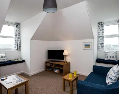 a living room with a blue couch and a tv at Pinewood 14 in Polzeath