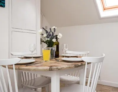 a dining room table with white chairs and a table with wine glasses at Pinewood 14 in Polzeath