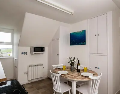a dining room with a table and white chairs at Pinewood 14 in Polzeath