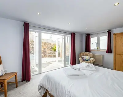 a bedroom with a bed and a large window at The Hideaway in Port Isaac