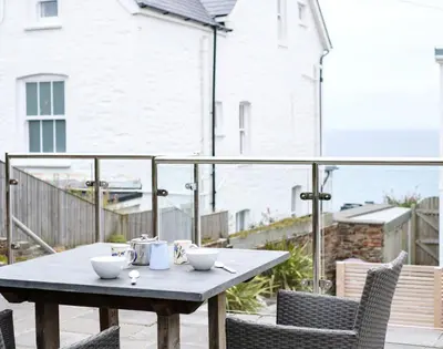 a table and chairs on a balcony with a table at The Hideaway in Port Isaac