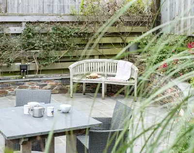 a patio with a table and a bench and a table and chairs at The Hideaway in Port Isaac