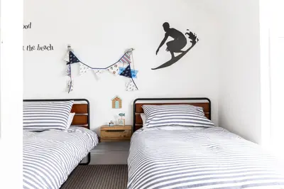 a bedroom with two beds and a surfboard on the wall at Number 28 in Port Isaac