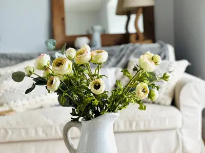 a white vase filled with white roses on a table at 1 Tintagel in Port Isaac