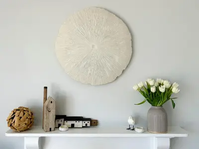 a white shelf with a vase of flowers and a mirror at 1 Tintagel in Port Isaac