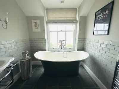 a large bath tub in a bathroom with a window at 1 Tintagel in Port Isaac