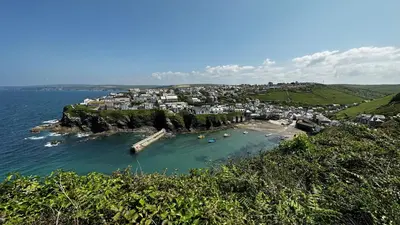 a small island in the ocean with boats in the water at 1 Tintagel in Port Isaac