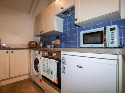 a kitchen with a microwave and a washer and dryer at Downrow Barn in Tintagel
