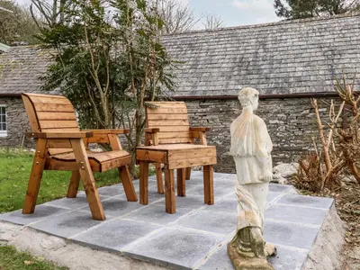 three wooden chairs and a statue of a boy at Downrow Barn in Tintagel