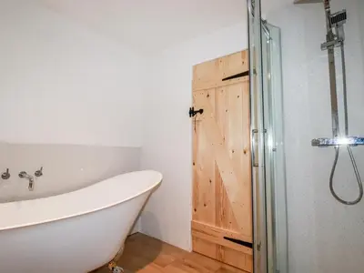 a bathroom with a bath tub and a sliding barn door at Downrow Barn in Tintagel