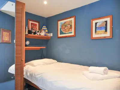 a bedroom with blue walls with a bed and shelves at Beachside in Polzeath