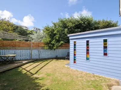 a white building with stained glass windows next to a fence at Beachside in Polzeath