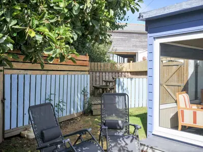 two chairs sitting in a yard next to a shed at Beachside in Polzeath