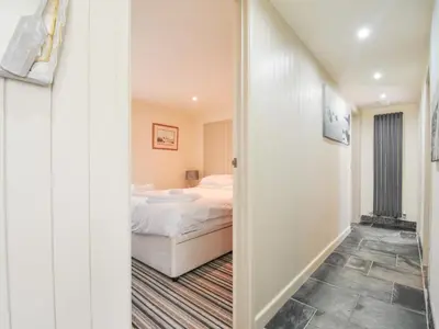 a bedroom with a bed and a hallway at Beachside in Polzeath