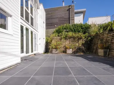 a courtyard of a house with a stone wall at Drishti in Polzeath